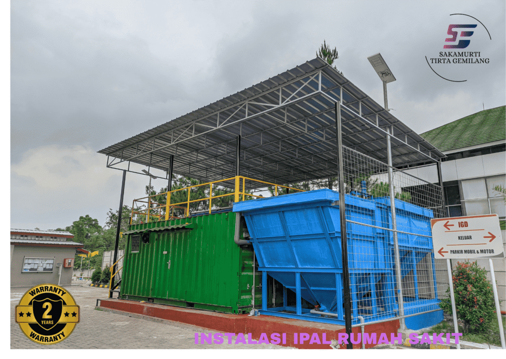 Unit instalasi IPAL rumah sakit model kontainer dan tangki biru dengan atap pelindung, hasil pengerjaan Sakamurti Tirta Gemilang di area parkir rumah sakit.